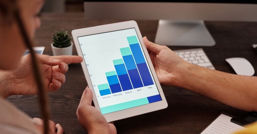 Two colleagues reviewing a bar chart on a tablet while auditing comment data