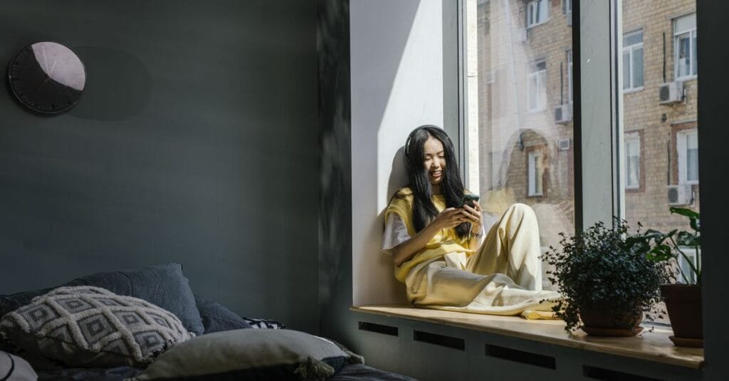 Woman with headphones smiling at a phone